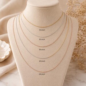 May include: A display of delicate chain necklaces in gold, silver, and rose gold, each with a different length. The lengths are labeled as 14 inch, 16 inch, 18 inch, 20 inch, and 24 inch. The necklaces are draped on a mannequin.