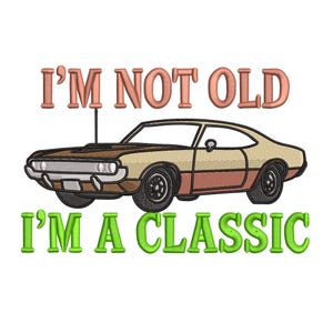 May include: An embroidered design featuring a classic car in tan, brown, and red, with the text "I'M NOT OLD" above and "I'M A CLASSIC" below, all on a white background.