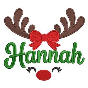 May include: A festive design featuring a reindeer face with the name "Hannah" in green script. The design includes brown antlers, a red bow, a red nose, and black eyelashes, perfect for holiday-themed crafts and gifts.