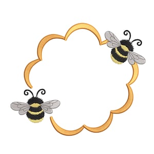 May include: A golden, cloud-shaped frame with two embroidered bumblebees. The bees have black and yellow striped bodies, gray wings, and black antennae. The frame is a warm, light brown color.