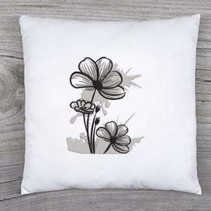 Puede incluir: Almohada bordada en blanco y negro con un dise&ntilde;o floral estilizado con tres flores y un fondo gris.