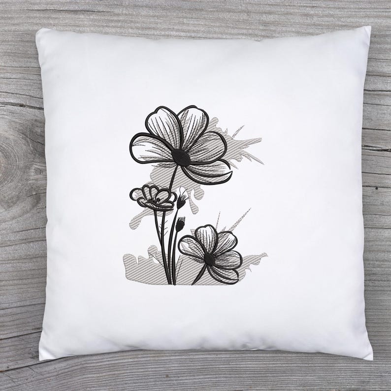 Puede incluir: Almohada bordada en blanco y negro con un dise&ntilde;o floral estilizado con tres flores y un fondo gris.
