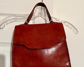 Bolso vintage Brahmin de piel marrón con asa superior y herrajes de bronce. Cierre de solapa.