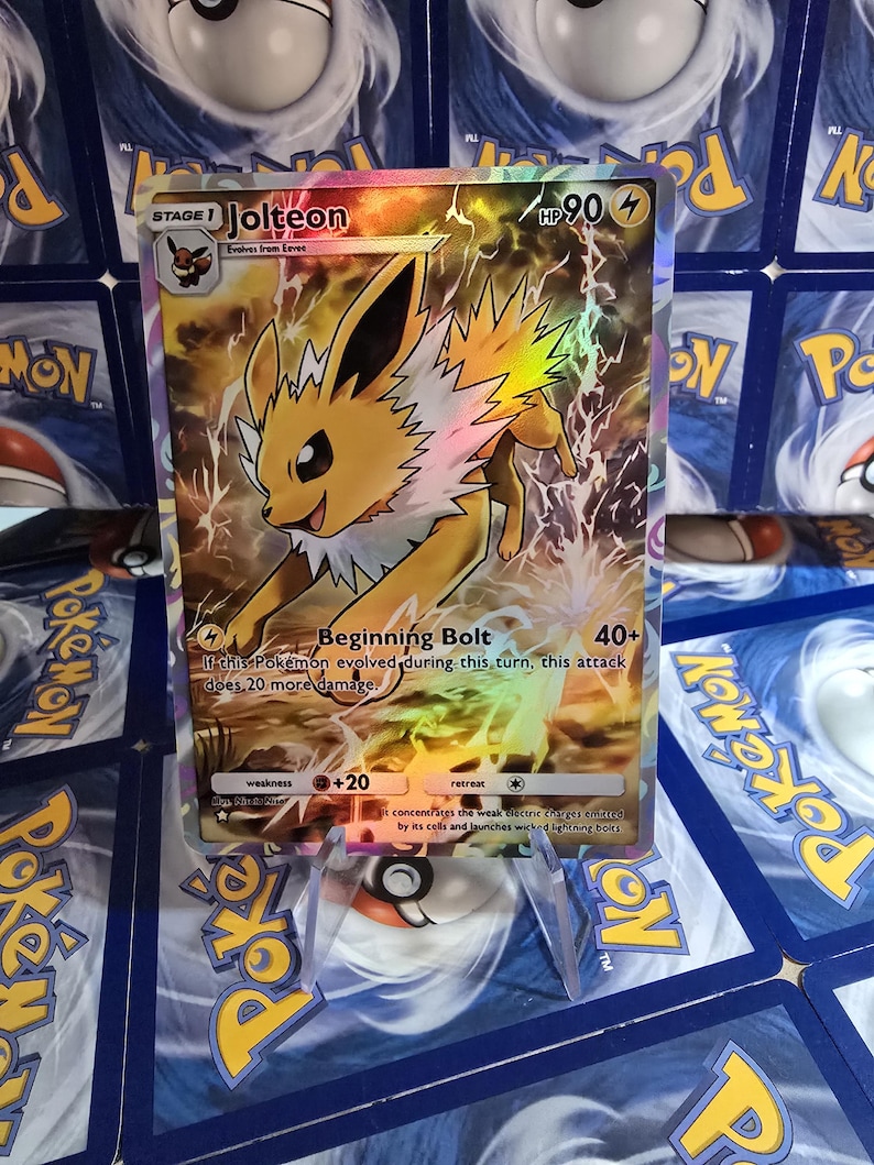 May include: A holographic Pok&eacute;mon card featuring Jolteon, a yellow electric-type Pok&eacute;mon. The card displays the text "Jolteon" and "Beginning Bolt", along with attack details and HP. The background is a mix of yellow and electric effects.