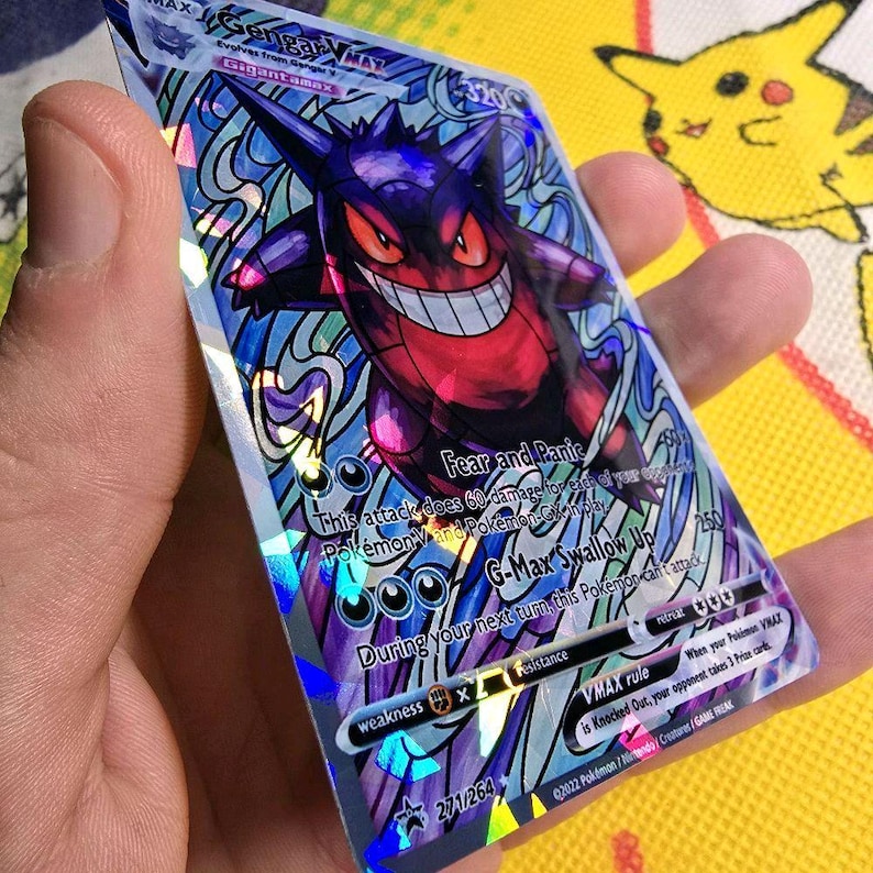 K&ouml;nnte beinhalten: Eine holografische Gengar VMAX Pok&eacute;mon-Sammelkarte. Die Karte zeigt einen lila und roten Gengar-Charakter mit einem breiten Grinsen, vor einem wirbelnden, schillernden Hintergrund. Der Text enth&auml;lt "Fear and Panic" und "G-Max Swallow Up".