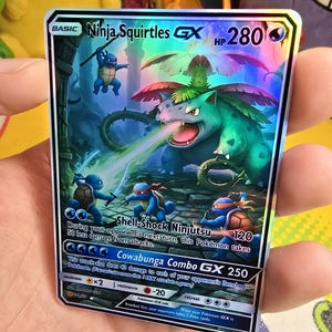 K&ouml;nnte beinhalten: Eine holografische Pok&eacute;mon-Karte mit "Ninja Squirtles GX" und 280 KP. Die Karte zeigt eine Kampfszene mit blauen, schildkr&ouml;tenartigen Kreaturen und einer gro&szlig;en, gr&uuml;nen, pflanzenartigen Kreatur. Die Karte hat Angriffsbezeichnungen und einen "Cowabunga Combo GX 250" Angriff.