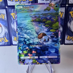 Peut inclure: Une carte de jeu de Pokemon bleue et violette représentant Squirtle, un Pokemon de type eau. La carte a une finition holographique et montre Squirtle nageant dans un étang. Le texte de la carte indique "BASIC Squirtle HP 60 Water Gun 20".