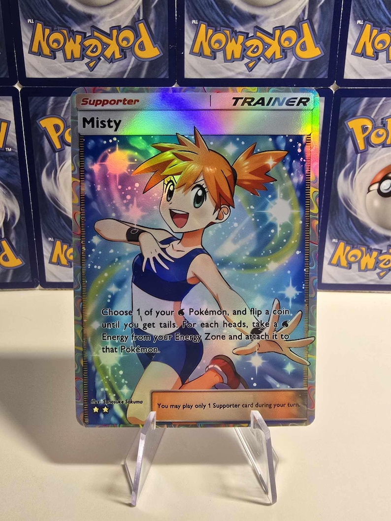 May include: A holographic Misty Trainer card from the Pok&eacute;mon Trading Card Game. The card features a colorful illustration of Misty, with text that reads "Choose 1 of your Pok&eacute;mon, and flip a coin."