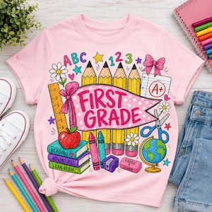 Könnte beinhalten: Ein hellrosa T-Shirt mit einem bunten Grafikdruck von Schulmaterialien, darunter gelbe Bleistifte, ein roter Apfel, Bücher mit der Aufschrift Reading Adventures und I Can Read, ein Globus, eine Schere und ein Banner mit First Grade.