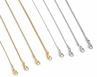 May include: Six delicate chain necklaces in gold and silver tones are displayed against a white background. Each chain has a lobster clasp closure. The chains are of varying lengths and are suitable for pendants.
