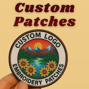 以下が含まれることがあります： 山、川、ヒマワリが描かれた風景デザインの丸い刺繍パッチ。「Custom Logo」と「Embroidery Patches」の文字が縁に書かれています。「Custom Patches」の文字がパッチの上に表示されています。