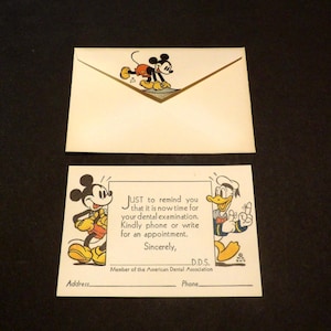 Puede incluir: Recordatorio de cita dental vintage con Mickey Mouse y el Pato Donald. La tarjeta crema incluye texto que recuerda al destinatario que programe un examen dental. El sobre también presenta a Mickey Mouse.