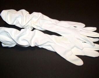 May include: A pair of long white gloves made of a soft, stretchy fabric. The gloves are bunched up and appear to be made of a lightweight material.