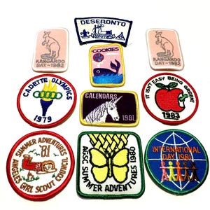 Puede incluir: Una colección de parches bordados vintage con varios diseños y texto. Los parches incluyen un canguro, una ballena, un unicornio, una antorcha, una mariposa y textos como "COOKIES", "1981" y "INTERNATIONAL DAY 1981".