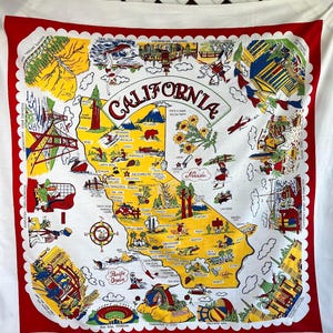 May include: A vintage California souvenir map printed on a white fabric with a red border. The map features illustrations of landmarks and attractions, with the word "CALIFORNIA" prominently displayed. The map includes the text "STATE FLOWER YELLOW POPPY".