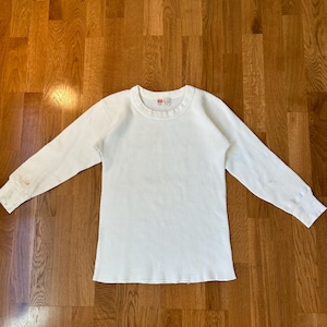 May include: White long-sleeve thermal shirt with a crew neck and a small red tag on the front that says "Levi's".