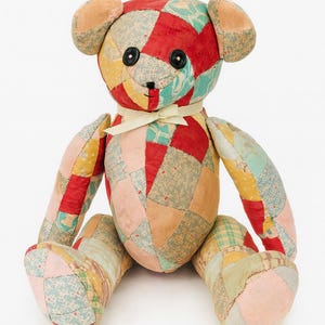 May include: A handmade patchwork teddy bear with a variety of colorful fabric patches. The bear has black button eyes, a stitched nose, and a cream-colored ribbon bow. The bear is approximately 18 inches tall.