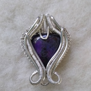 May include: A silver wire wrapped pendant featuring a heart-shaped purple gemstone.