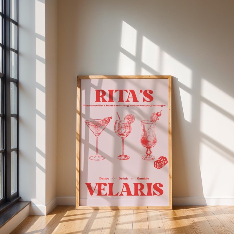 May include: A pink poster with the text "Rita's" in red, with the words "Welcome to Rita's. Drinks are strong and the company is stronger" in smaller red text. The poster features three red illustrations of cocktails, with the words "Dance", "Drink", and "Games" below the illustrations. The poster also has the text "Velaris" in large red letters at the bottom.