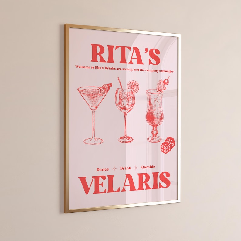 May include: A pink poster with a gold frame featuring the text "RITA'S" in red. The poster also includes the text "Welcome to Rita's. Drinks are strong and the company's stronger" and "Dance Drink Gamble VELARIS" in red. The poster features three red line drawings of cocktails.