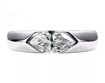 May include: A silver ring featuring a marquise-cut diamond. The diamond is set in a bezel setting, and the band is smooth and polished. The ring is a classic and elegant piece of jewelry.