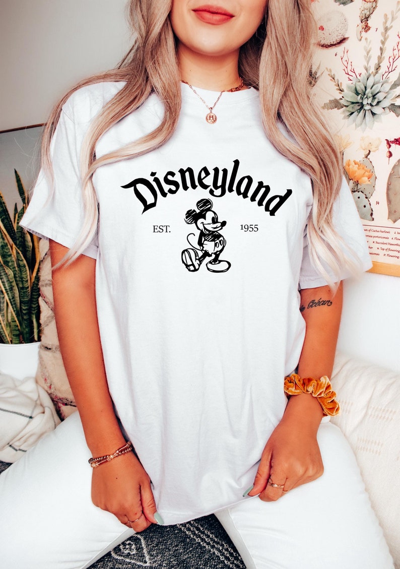 May include: White t-shirt with a black and white graphic of Mickey Mouse and the text "Disneyland Est. 1955"