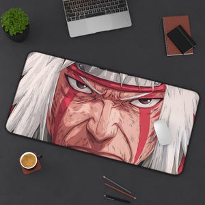 Puede incluir: Alfombrilla de ratón rectangular con una ilustración detallada de un personaje con cabello blanco y marcas rojas. La cara del personaje es el punto focal, con una expresión intensa. La alfombrilla tiene bordes negros y está diseñada para uso informático.