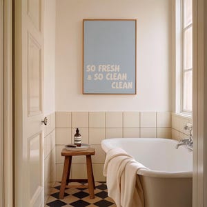Printable wall art says "So Fresh & So Clean Clean" , displayed above a bathtub.