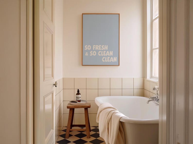 Printable wall art says "So Fresh & So Clean Clean" , displayed above a bathtub.