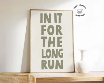 Pode incluir: Impressão emoldurada com o texto "IN IT FOR THE LONG RUN" em verde sálvia. A impressão é exibida em uma superfície de madeira com um vaso branco à direita. As palavras estão em negrito, fonte sem serifa. Download imediato.