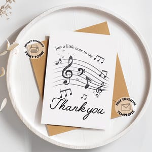 Puede incluir: Tarjeta de felicitación blanca con notas musicales y la frase "just a little note to say Thank you" en escritura negra. La tarjeta está sobre un sobre marrón, colocado en una bandeja blanca. Elementos decorativos: notas musicales y clave de sol.