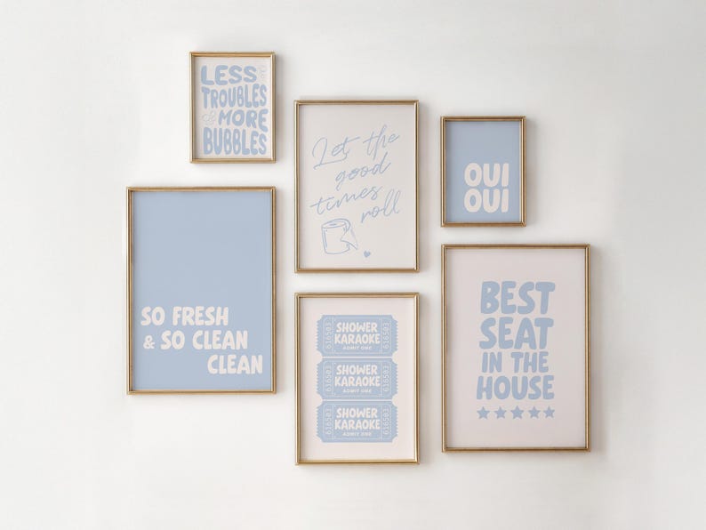 A set of 6 funny pastel blue toned bathroom prints with gold frames, displaying text-based designs in blue and white. The artwork includes phrases such as "Shower Karaoke", "Oui Oui" and "Less Troubles & More Bubbles", suitable for bathroom decor.