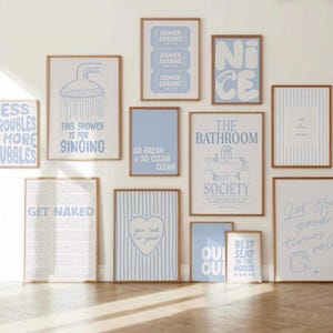 May include: A gallery wall set of twelve framed prints featuring light blue and white color schemes. The posters display various bathroom-themed typography and illustrations, including phrases like "Less Troubles More Bubbles," "Shower Karaoke," "The Bathroom Society," and "Get Naked," arranged in a decorative grid layout.
