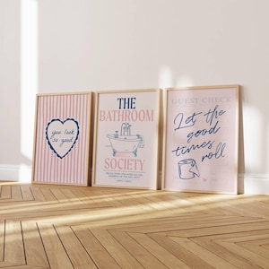 Pode incluir: Três quadros de parede com tema de banheiro. O primeiro apresenta listras rosas e um coração com o texto "you look so good". O segundo mostra uma ilustração de banheira com "THE BATHROOM SOCIETY". O terceiro é uma conta com "Let the good times roll" e um rolo de papel higiênico.