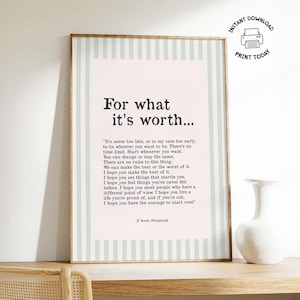 May include: A framed print with the text "For what it's worth..." in a stylish font. The print has a light pink background with a light green striped border. A white vase sits on a wooden shelf below.