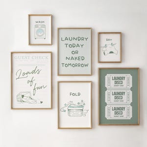 May include: A collection of framed art prints with a laundry theme. The prints feature illustrations of a washing machine, clothes on a line, and laundry-related text. The color palette includes gold frames, white backgrounds, and green and blue accents.