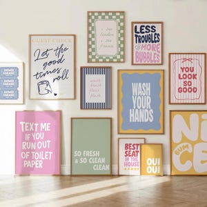 May include: A gallery wall collection of twelve rectangular framed prints featuring various typography and graphic designs in pastel and bold colours, including phrases like Let the good times roll, Wash your hands, and Nice bum, displayed on a wall.