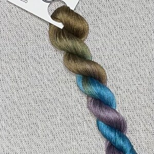 May include: A skein of hand-dyed embroidery floss in shades of green, blue, and purple. The floss is labeled "Dyeing for Cross Stitch" and "Hand Dyed Fabric and Floss".