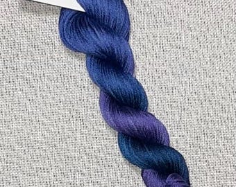 May include: A skein of hand-dyed cotton embroidery floss in shades of blue and purple. The floss is labeled "Dyeing for Cross Stitch" and "Hand Dyed Fabric and Floss".