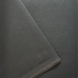 May include: Close-up of a dark grey fabric with a contrasting orange stitch along the edge.