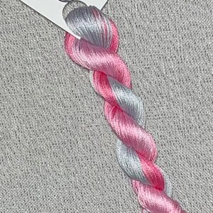May include: A skein of hand-dyed embroidery floss in a gradient of pink and silver. The floss is labeled "Dyeing for Cross Stitch" and "Hand Dyed Fabric and Floss".
