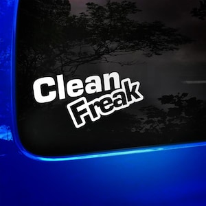 May include: A white vinyl decal with the text "Clean Freak" in black lettering. The decal is on a blue car window.