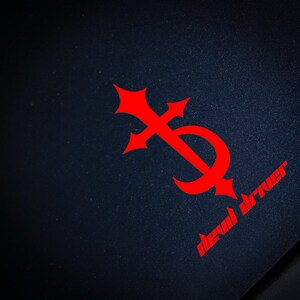 May include: A red stylised cross with a crescent moon shape, with the text "dead driver" below it on a dark blue background.