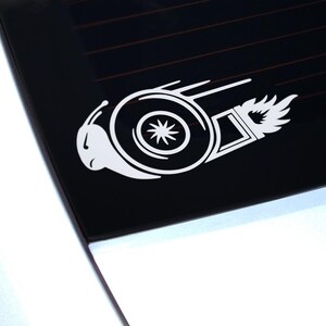 May include: White vinyl decal of a turbocharger with a snail shell design. The turbocharger is stylized with a flame coming out of the exhaust.