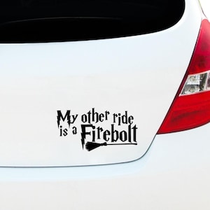 Op de afbeelding: Zwarte vinyl auto sticker met de tekst "My other ride is a Firebolt" op een witte auto. Het ontwerp bevat een bliksemschicht en een bezem, geïnspireerd op een fictieve bezem.