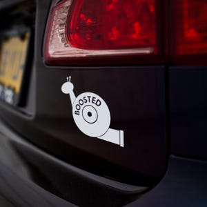May include: A white vinyl sticker of a snail with a turbocharger shell, the words "BOOSTED" are printed on the shell.