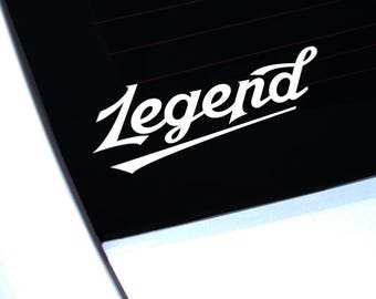 May include: White vinyl decal featuring the word "Legend" in a stylish cursive script. The decal is set against a black background, possibly a car window, with the white car body visible at the bottom.