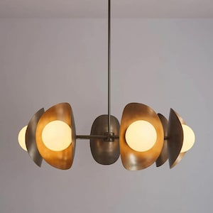 May include: A modern chandelier with a bronze finish. The light fixture features a central stem with a series of curved, metallic shades, each housing a spherical light bulb. The design is symmetrical and contemporary, suitable for interior lighting.