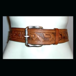 May include: A brown leather belt with a silver buckle. The belt is decorated with an intricate embossed pattern.