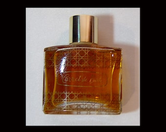 May include: A clear glass bottle of Carrel de Nuit perfume with a gold cap. The bottle has a grid pattern on the front and the name of the perfume is printed in gold.